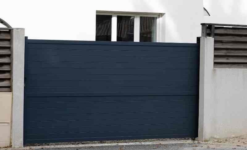 Anthrazitfarbenes Schiebetor mit waagerechter Blechfüllung in einer Grundstückseinfahrt